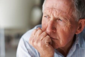 Closeup of a lonely senior man lost in thought , looking away