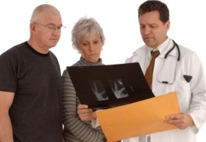 Doctor reviewing X-Ray film with senior couple on a white background