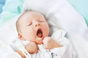 A baby yawns after entering the world and meeting his parents. 