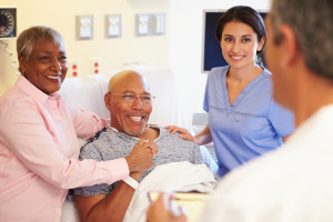 Medical Team Meeting With Senior Couple In Hospital Room